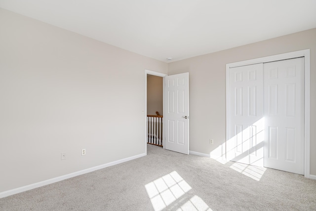 unfurnished bedroom with baseboards, a closet, and light colored carpet