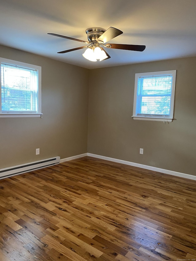 spare room featuring a baseboard heating unit, baseboards, wood finished floors, and a ceiling fan