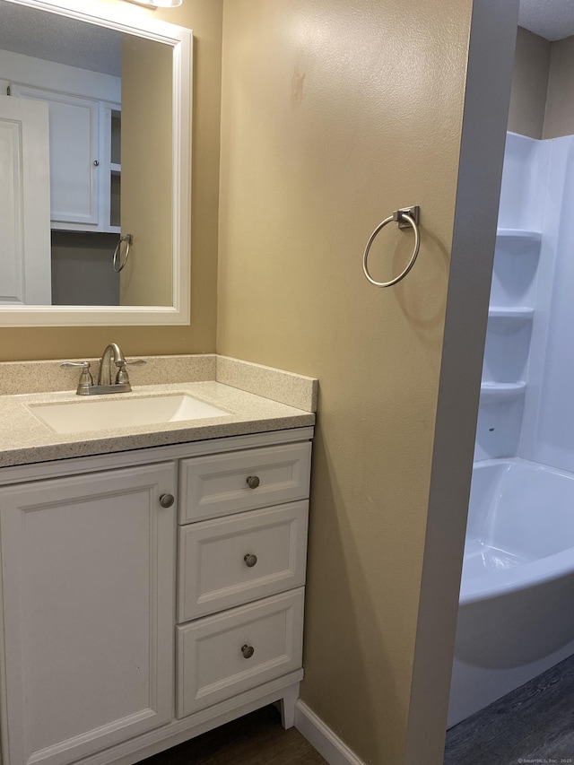 bathroom featuring bathtub / shower combination, vanity, and baseboards