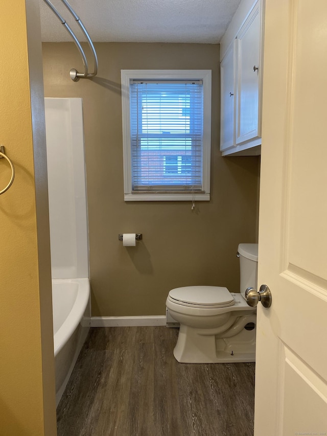 bathroom with toilet, wood finished floors, baseboards, and a textured ceiling