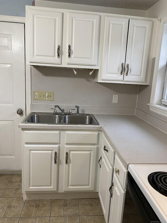 kitchen featuring a sink, white cabinets, electric range oven, and light countertops