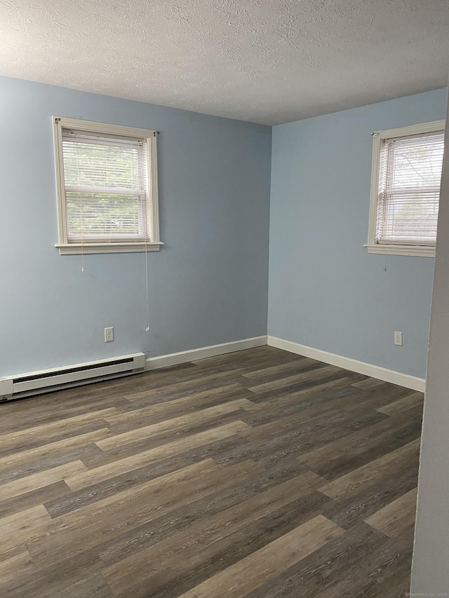 empty room featuring baseboards, baseboard heating, a healthy amount of sunlight, and dark wood-style floors