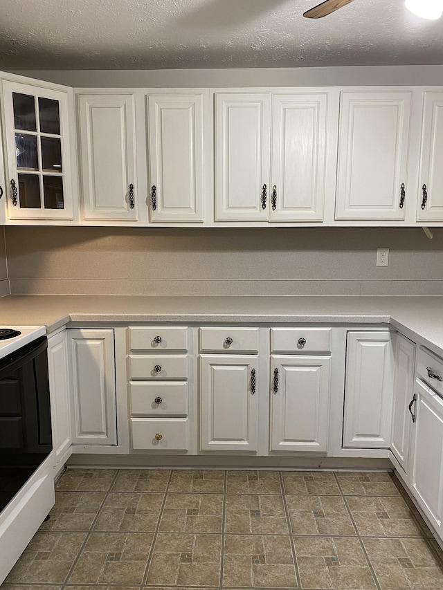 kitchen featuring glass insert cabinets, ceiling fan, light countertops, electric stove, and white cabinets