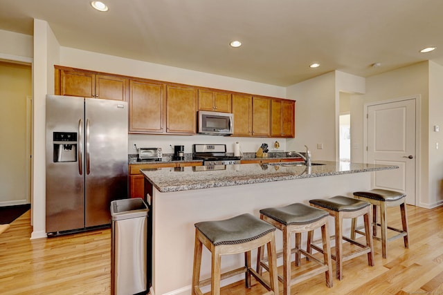 kitchen with light wood-type flooring, a sink, brown cabinets, and appliances with stainless steel finishes