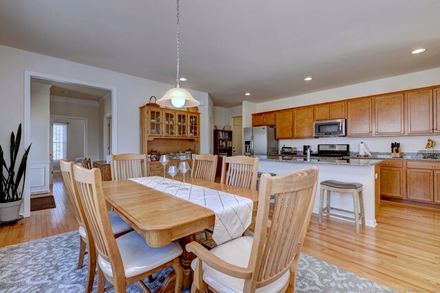 dining space featuring a wainscoted wall, light wood-style flooring, and recessed lighting