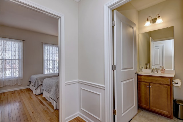 interior space with light wood-style flooring, a sink, and a wainscoted wall