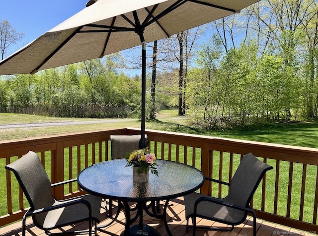 wooden deck with a lawn and outdoor dining area