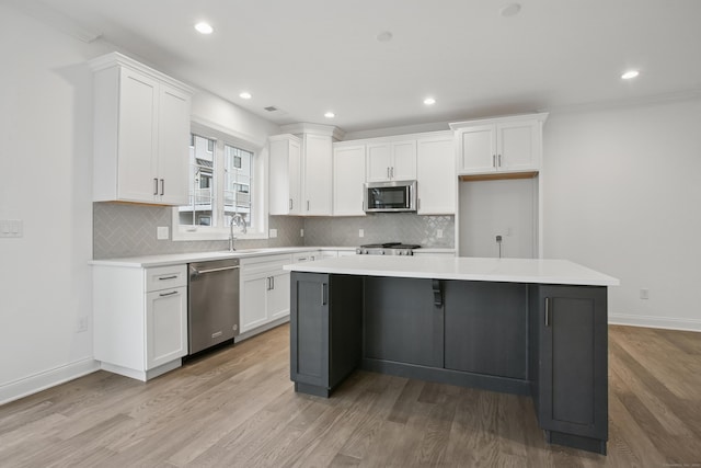 kitchen with stainless steel appliances, light wood-style flooring, white cabinets, and a center island