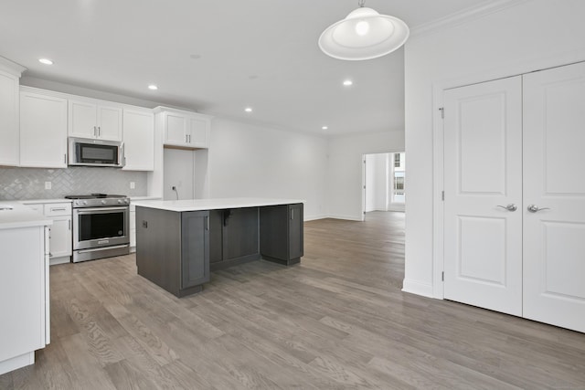 kitchen featuring white cabinets, appliances with stainless steel finishes, a center island, tasteful backsplash, and crown molding