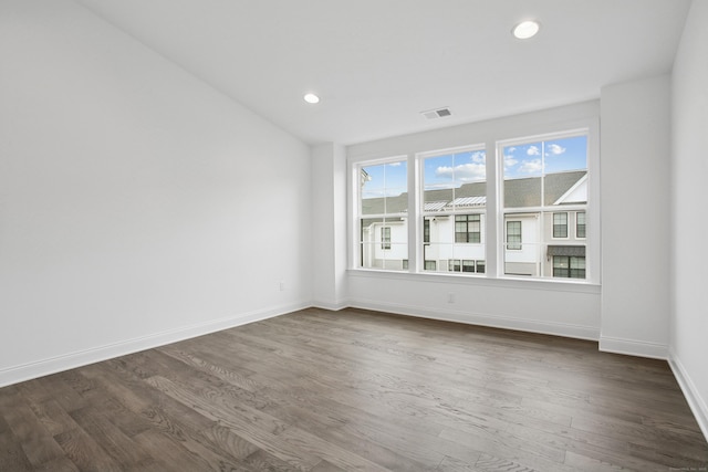 spare room featuring dark wood-style floors, visible vents, baseboards, and recessed lighting