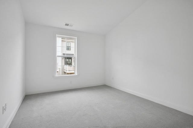 carpeted spare room featuring visible vents and baseboards