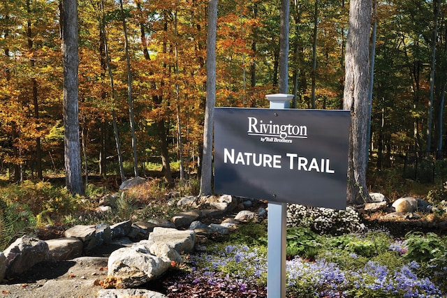 community / neighborhood sign featuring a view of trees