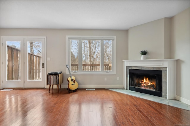 unfurnished room with baseboards, wood-type flooring, a healthy amount of sunlight, and a fireplace