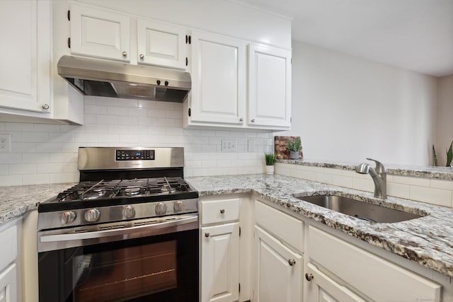 kitchen featuring decorative backsplash, gas stove, under cabinet range hood, and a sink