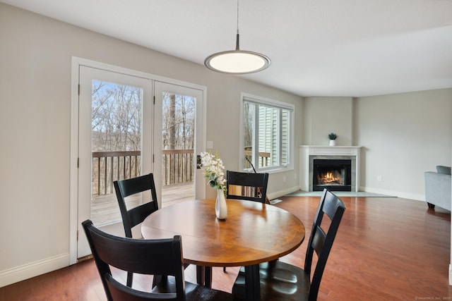 dining room featuring a fireplace, wood finished floors, and baseboards