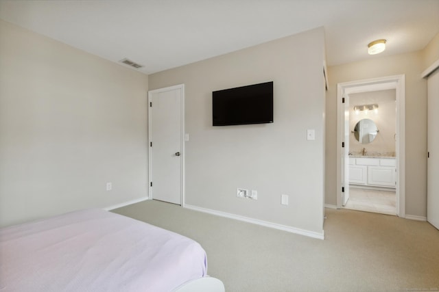 bedroom featuring visible vents, light carpet, a sink, ensuite bath, and baseboards