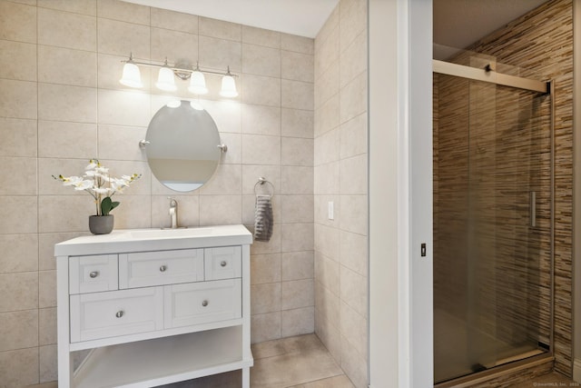 full bath with vanity, a shower stall, and tile walls