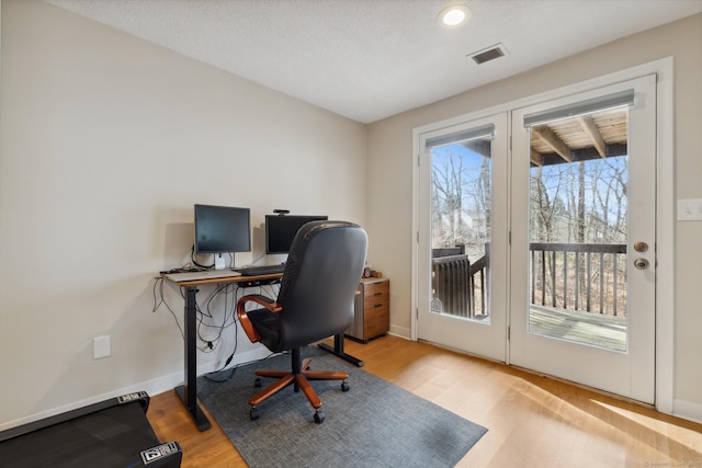 home office featuring visible vents, baseboards, and wood finished floors