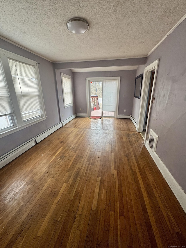 unfurnished living room featuring crown molding, baseboards, visible vents, and wood-type flooring