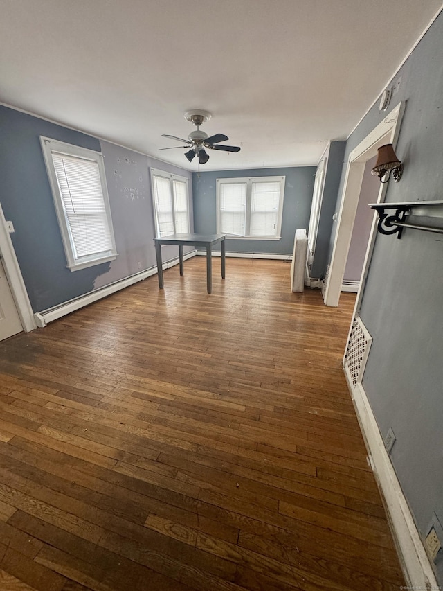 interior space featuring visible vents, a baseboard heating unit, baseboards, dark wood-style floors, and a ceiling fan