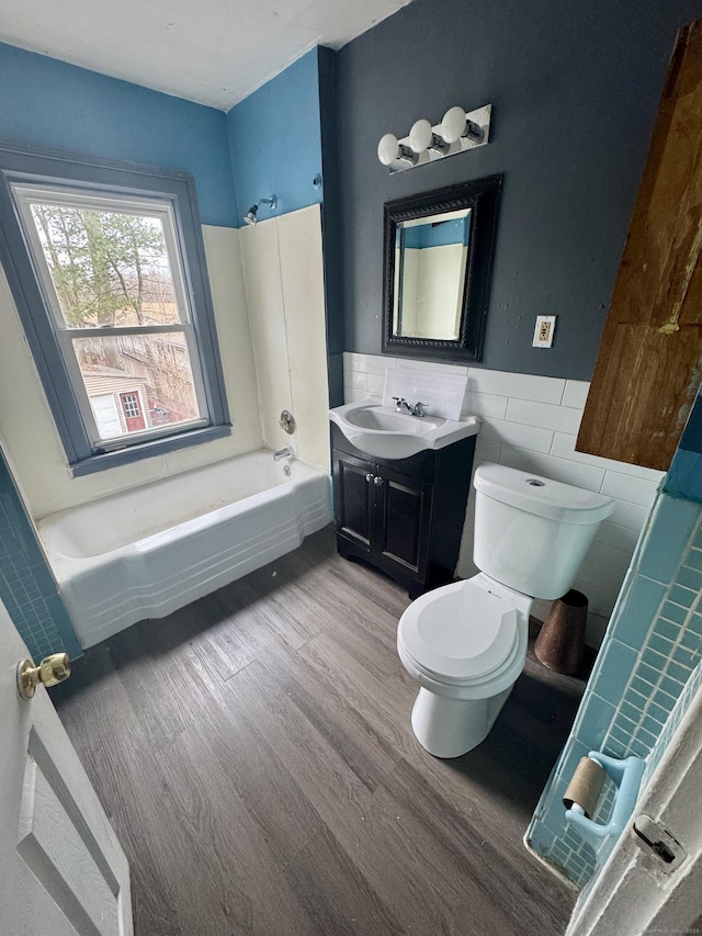 bathroom with vanity, wood finished floors, wainscoting, tile walls, and toilet