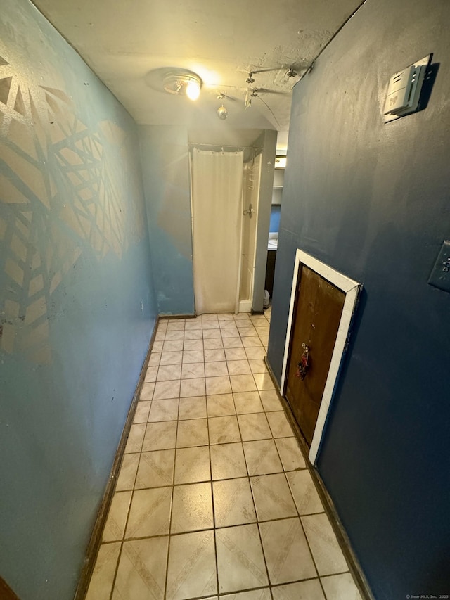 hall featuring light tile patterned flooring and baseboards