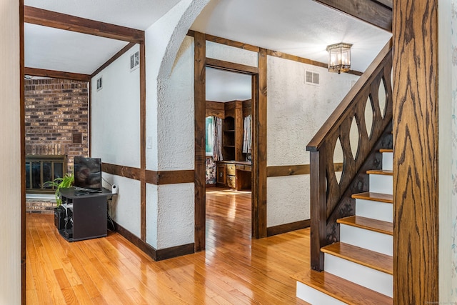 stairs featuring visible vents, beamed ceiling, an inviting chandelier, and wood finished floors