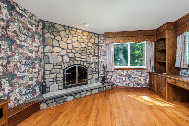 unfurnished living room with hardwood / wood-style flooring, a fireplace, and baseboards