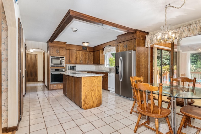 kitchen featuring a center island, light countertops, beam ceiling, appliances with stainless steel finishes, and a notable chandelier