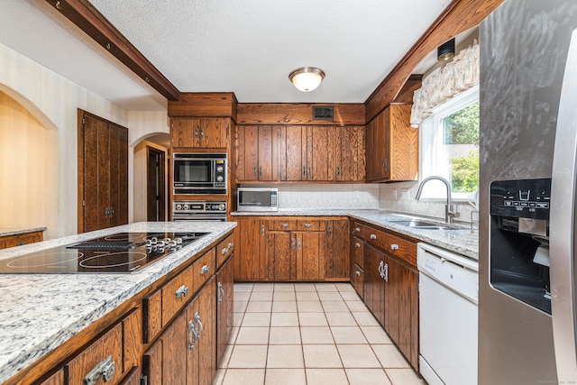 kitchen featuring black appliances, a sink, backsplash, arched walkways, and light tile patterned floors