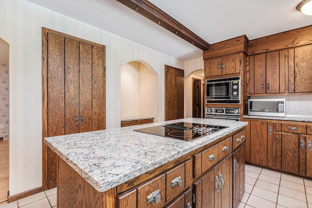 kitchen with black appliances, a kitchen island, arched walkways, brown cabinetry, and light tile patterned floors