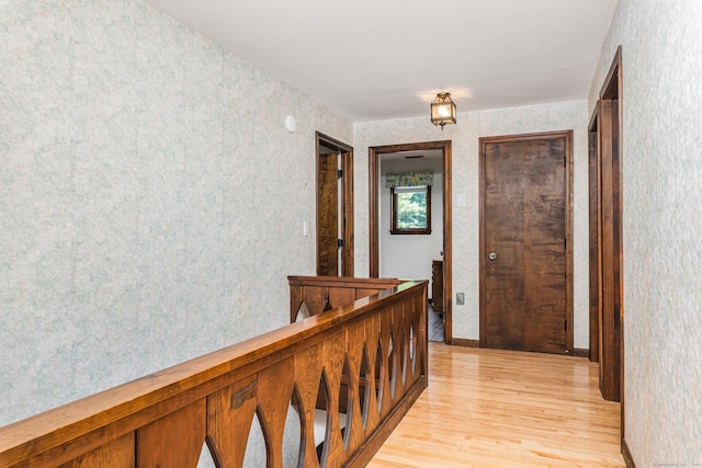 hallway featuring light wood-style flooring and wallpapered walls