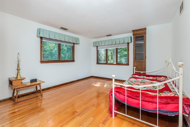 bedroom with visible vents, baseboards, and wood finished floors
