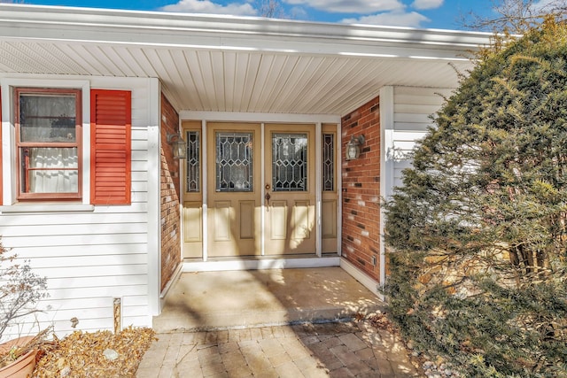 entrance to property with brick siding and a porch