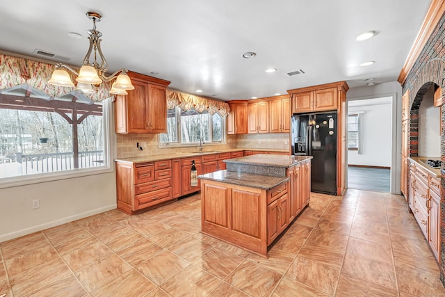 kitchen featuring visible vents, black fridge with ice dispenser, a kitchen island, a sink, and backsplash