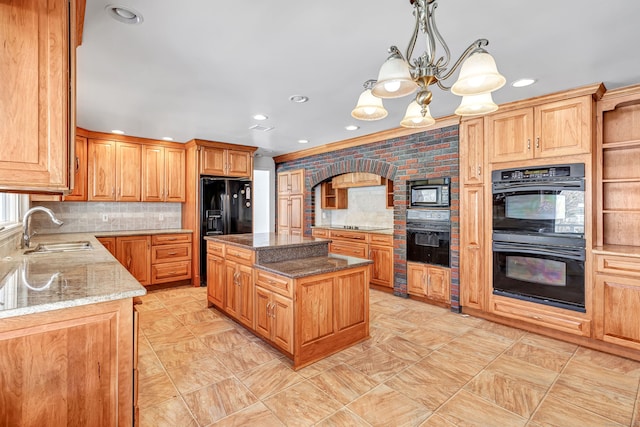 kitchen with light stone counters, a sink, a kitchen island, a chandelier, and black appliances