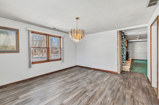 spare room with visible vents, a textured ceiling, and wood finished floors