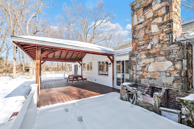 snow covered deck featuring an outdoor stone fireplace and a gazebo