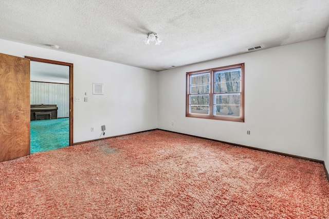 carpeted empty room featuring baseboards, visible vents, and a textured ceiling