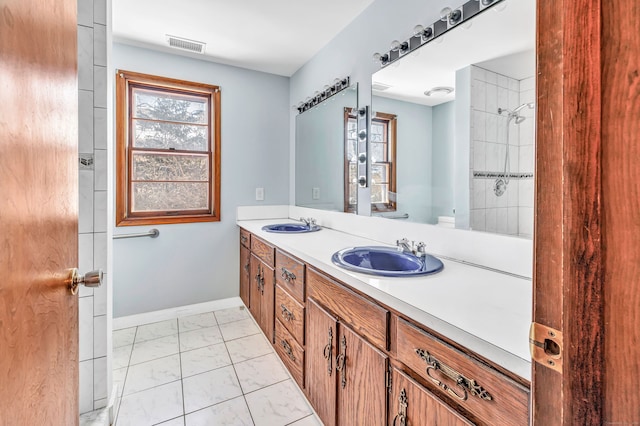 bathroom featuring double vanity, visible vents, baseboards, and a sink