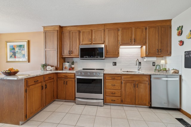 kitchen with a sink, brown cabinetry, and stainless steel appliances