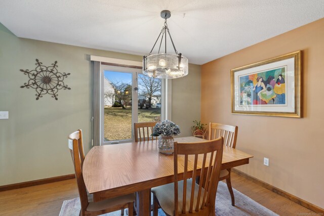 dining area with a notable chandelier, light wood-type flooring, and baseboards