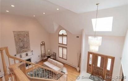 entrance foyer with vaulted ceiling, wood finished floors, a fireplace, and a chandelier