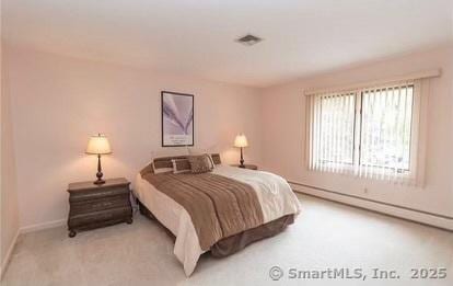 carpeted bedroom with visible vents and a baseboard radiator