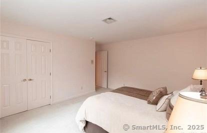 bedroom featuring visible vents, light colored carpet, and a closet