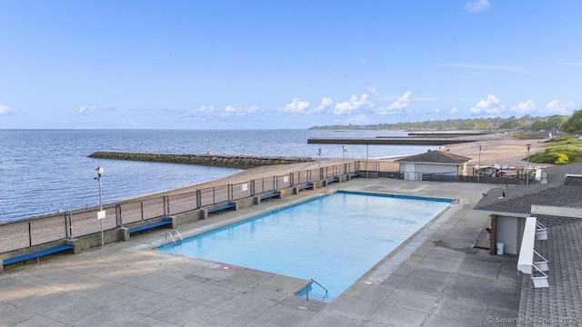 community pool with a patio, a water view, and fence