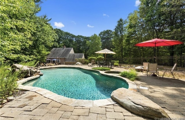 view of swimming pool featuring fence, outdoor dining area, a fenced in pool, and a patio