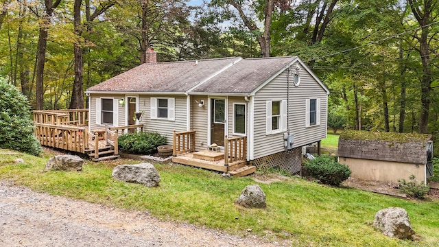 ranch-style home featuring an outbuilding, a chimney, and a front lawn