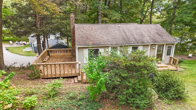 back of property with a chimney and a wooden deck