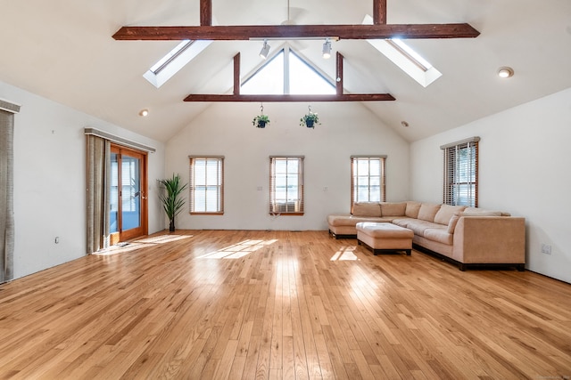 unfurnished living room with high vaulted ceiling, beam ceiling, a skylight, and light wood-style flooring